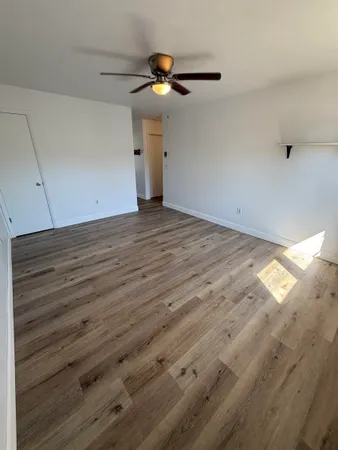 a view of a room with wooden floor and a ceiling fan