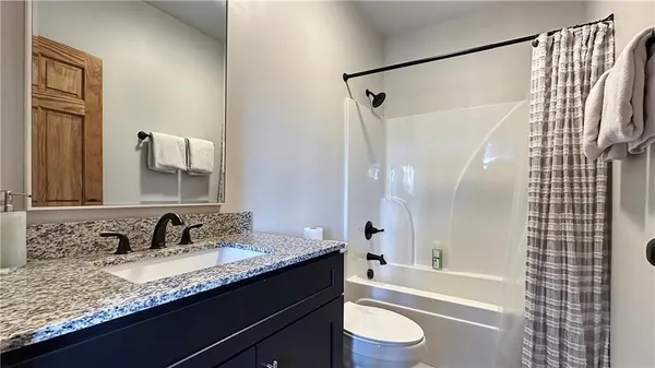 a bathroom with a granite countertop sink toilet a shower and a mirror