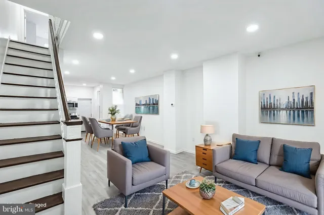 a living room with furniture kitchen view and a wooden floor