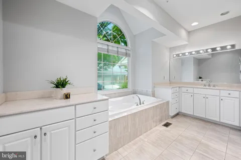 a spacious bathroom with a double vanity sink a large mirror a bathtub and window