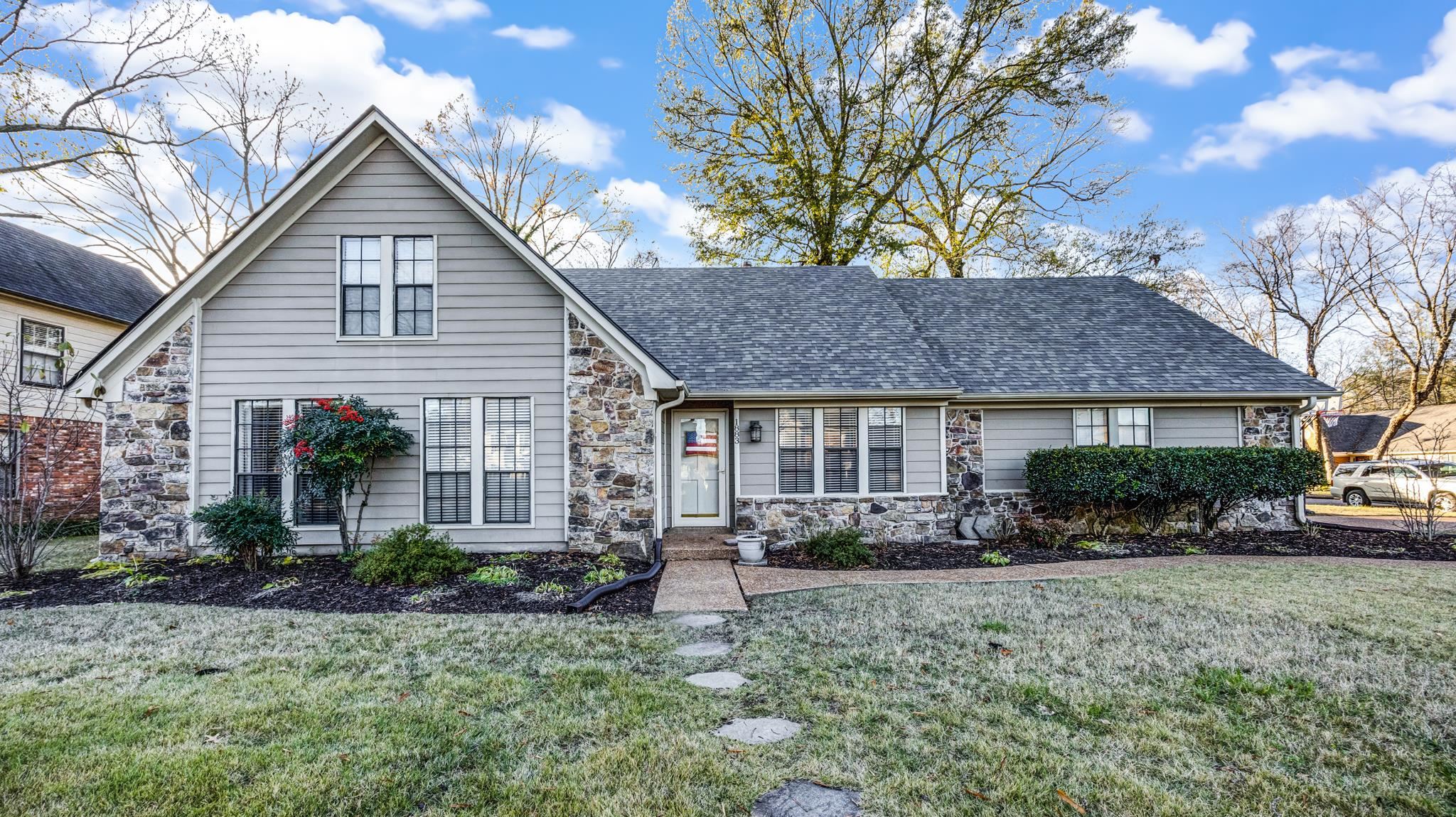 a front view of a house with a yard and potted plants