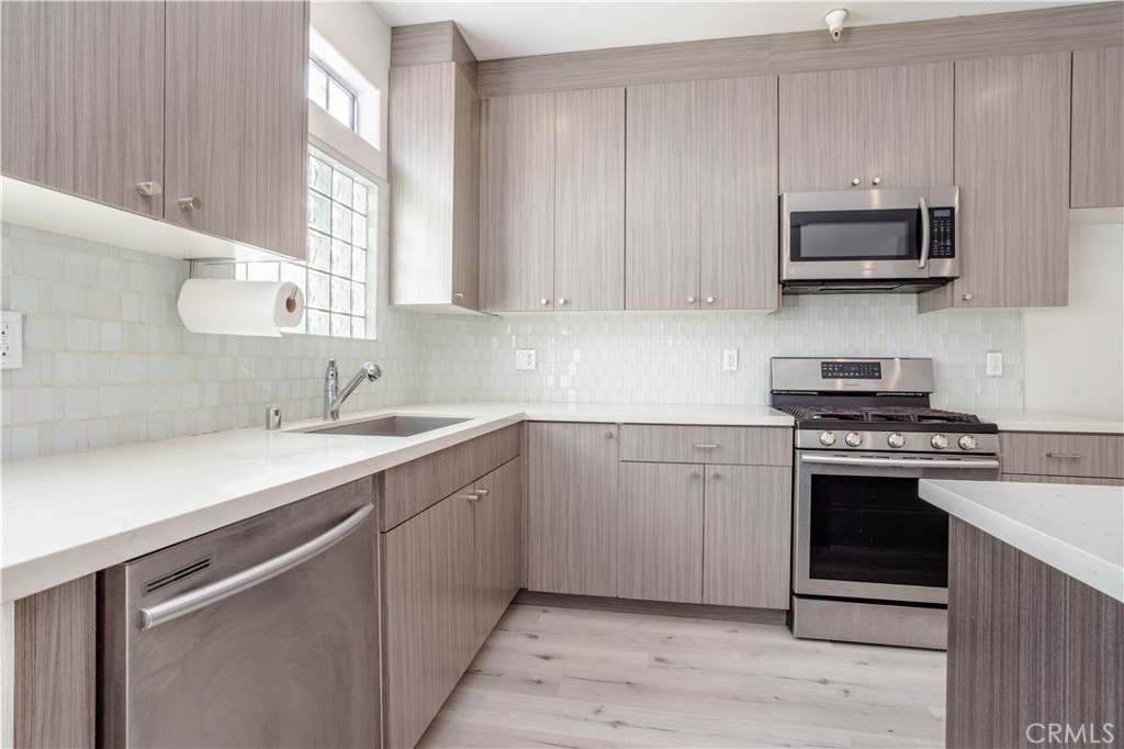 18347 Saticoy Street, Unit 28 Reseda, CA 91335 - Photo 11 of 27 a kitchen with stainless steel appliances granite countertop a sink dishwasher a stove and a microwave oven with cabinets