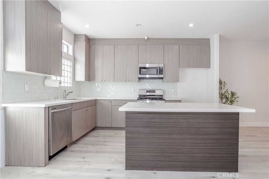 18347 Saticoy Street, Unit 28 Reseda, CA 91335 - Photo 12 of 27 a kitchen with kitchen island granite countertop a sink window and cabinets