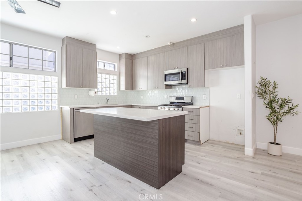 18347 Saticoy Street, Unit 28 Reseda, CA 91335 - Photo 10 of 27 a kitchen with kitchen island white cabinets and window