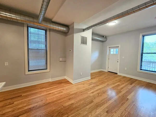 a view of an empty room with wooden floor and a window