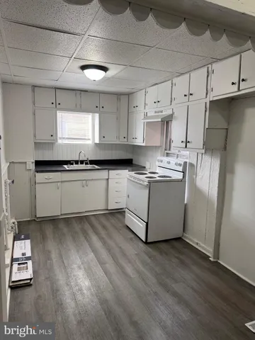 a kitchen with stainless steel appliances granite countertop a sink a stove a refrigerator and island with wooden floor