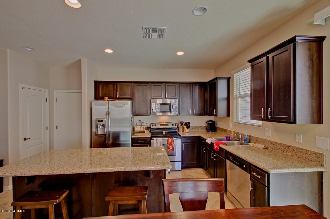 4073 East Tulsa Street Gilbert, AZ 85295 - Photo 12 of 33 a kitchen with kitchen island a stove a sink and a refrigerator