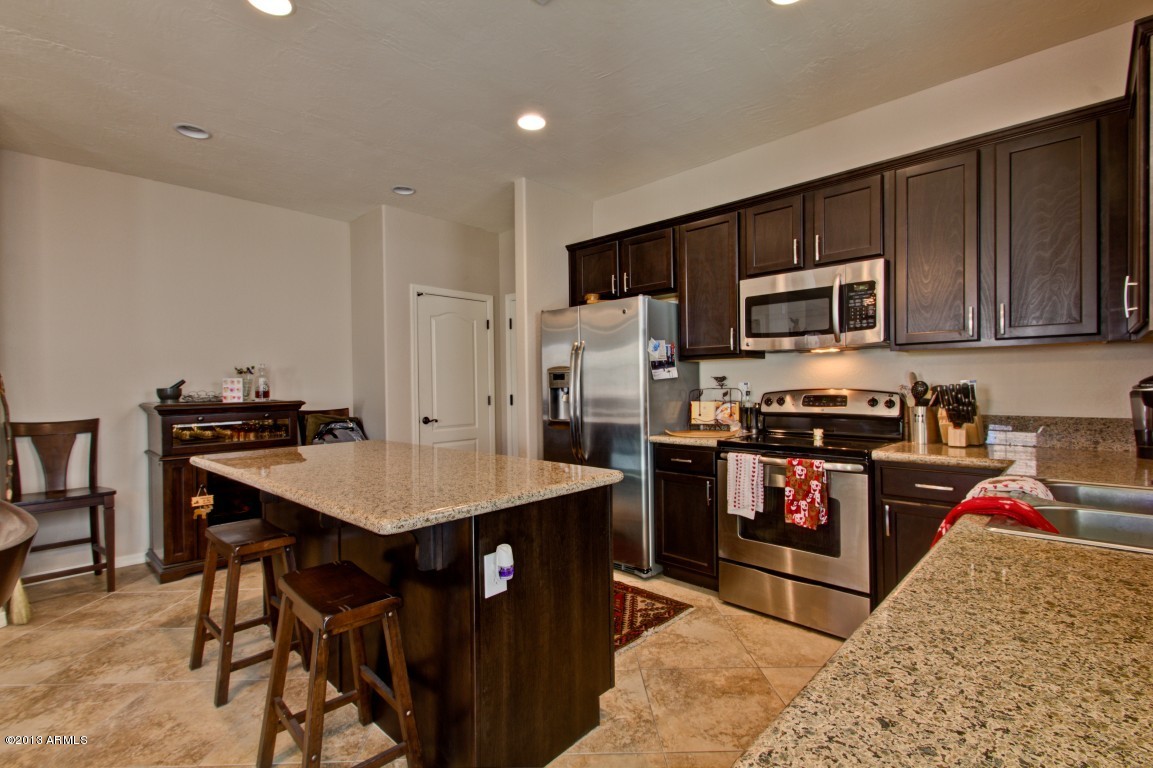 4073 East Tulsa Street Gilbert, AZ 85295 - Photo 10 of 33 a kitchen with stainless steel appliances granite countertop a stove top oven a sink dishwasher and a refrigerator with wooden cabinets