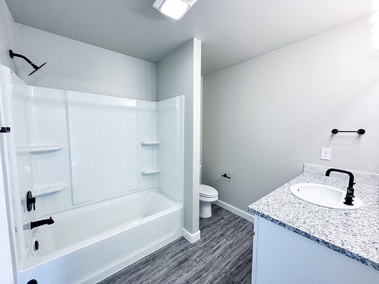 6928 10th Street Lubbock, TX 79416 - Photo 21 of 23 a bathroom with a granite countertop sink toilet and bathtub