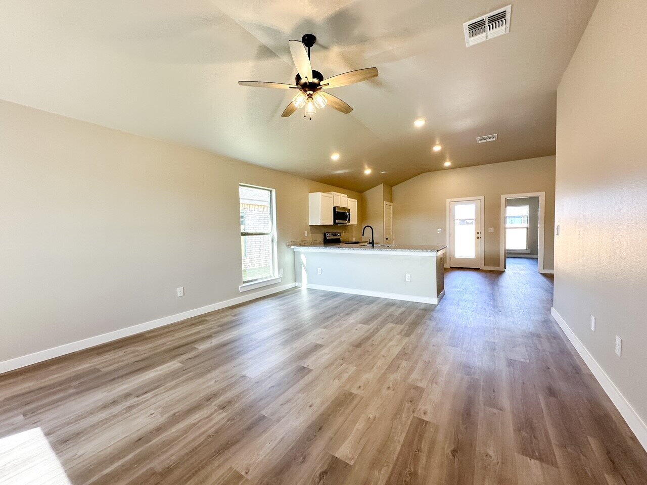 6928 10th Street Lubbock, TX 79416 - Photo 3 of 23 a view of a big room with wooden floor and a kitchen view
