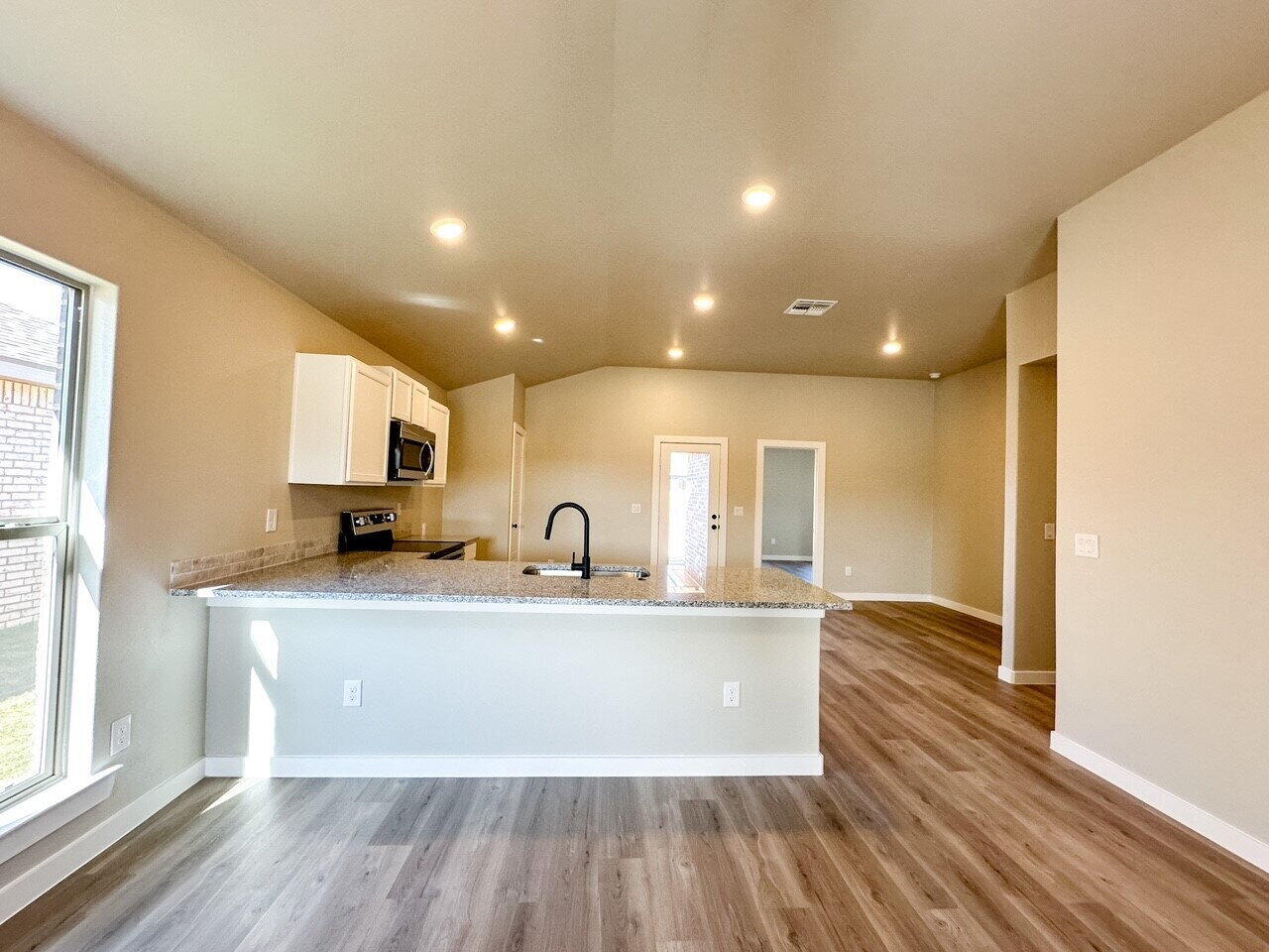 6928 10th Street Lubbock, TX 79416 - Photo 5 of 23 a large kitchen with stainless steel appliances a large window a sink and a oven