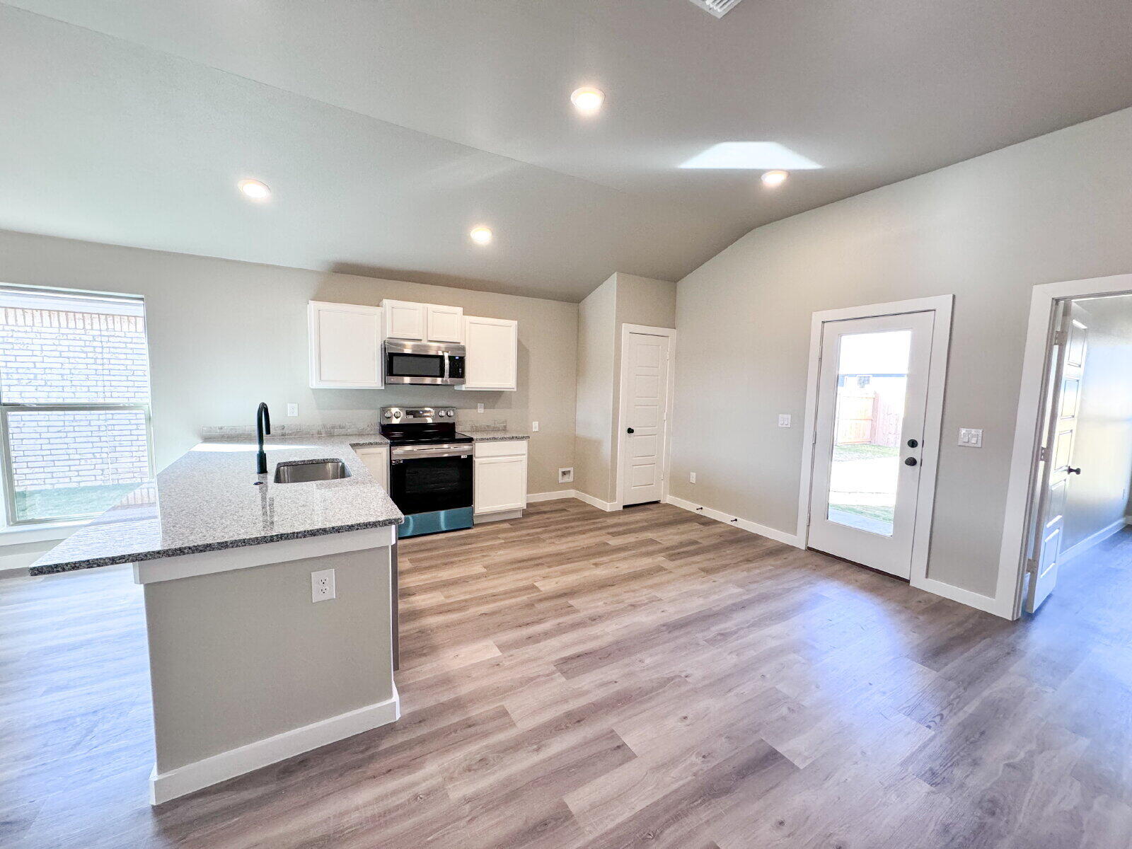 6928 10th Street Lubbock, TX 79416 - Photo 6 of 23 a kitchen with sink cabinets and wooden floor
