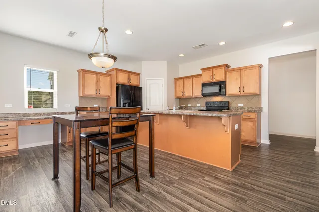 a kitchen with stainless steel appliances kitchen island granite countertop wooden floors and wooden cabinets