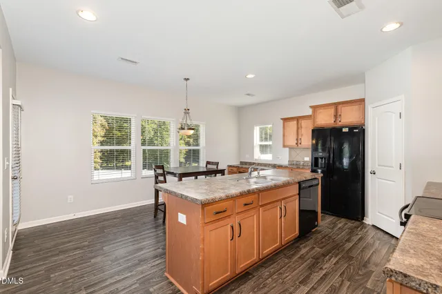 a kitchen with a stove a refrigerator a sink and wooden floor