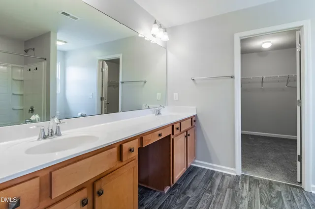 a spacious bathroom with a double vanity sink a mirror and shower