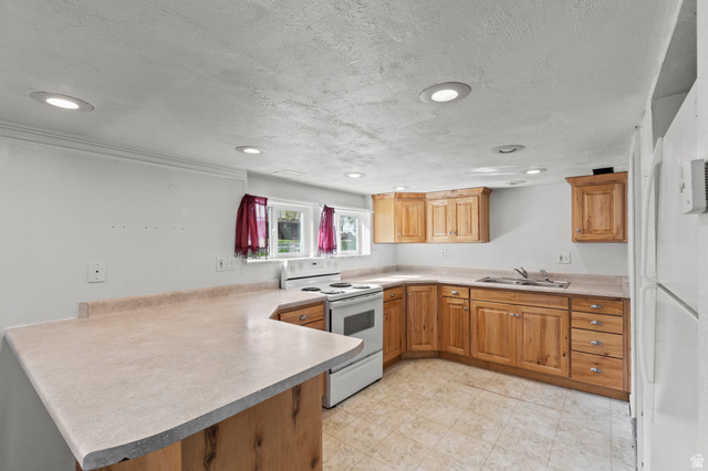 180 South 300 East Logan, UT 84321 - Photo 21 of 35 Kitchen with a peninsula, white appliances, light countertops, light floors, and a textured ceiling