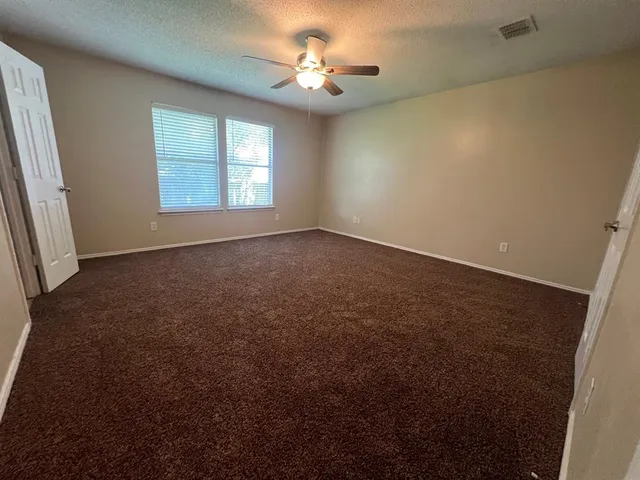 an empty room with windows and fan