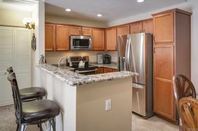 a kitchen with stainless steel appliances granite countertop a refrigerator a stove a sink a dining table and chairs