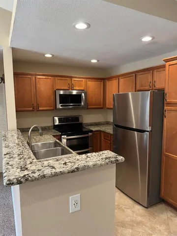 a kitchen with stainless steel appliances granite countertop a refrigerator a stove a sink and a microwave