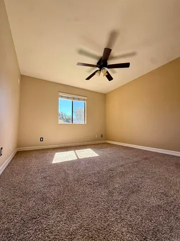 an empty room with a ceiling fan and a window