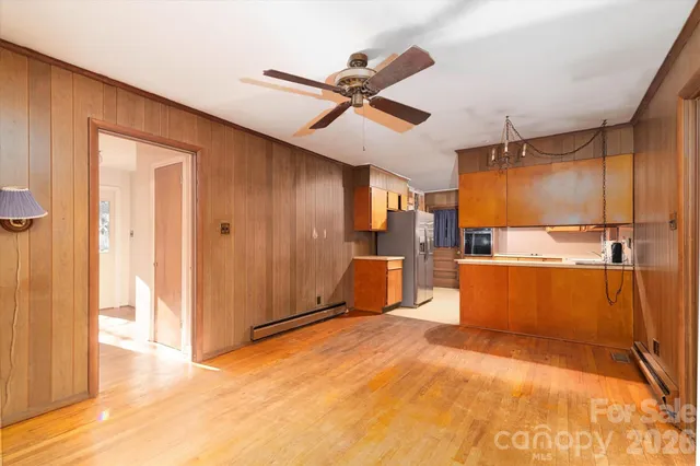 an empty room with a chandelier fan and windows