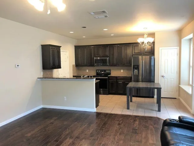 a kitchen with kitchen island granite countertop a stove a sink a refrigerator and a microwave