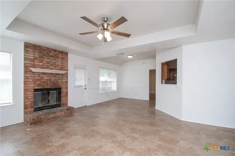 an empty room with windows fireplace and fan