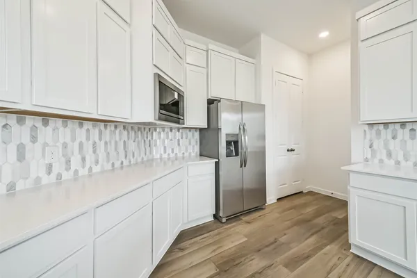 a kitchen with granite countertop white cabinets and refrigerator