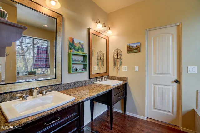 a bathroom with a granite countertop sink a mirror and a wooden floor