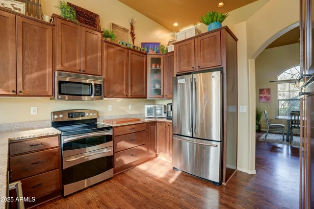 a kitchen with granite countertop wooden floors stainless steel appliances and cabinets