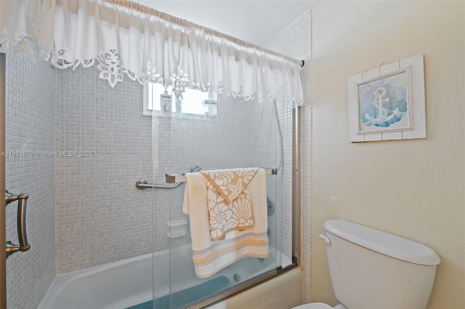 3140 Holiday Springs Boulevard, Unit 9102 Margate, FL 33063 - Photo 27 of 35 a bathroom with a shower curtain and a toilet