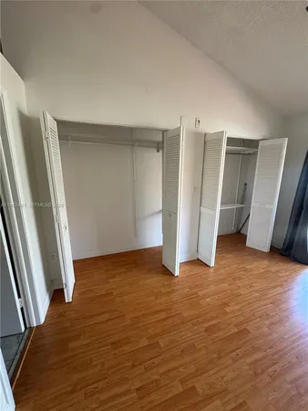 a view of an empty room with wooden floor and stairs
