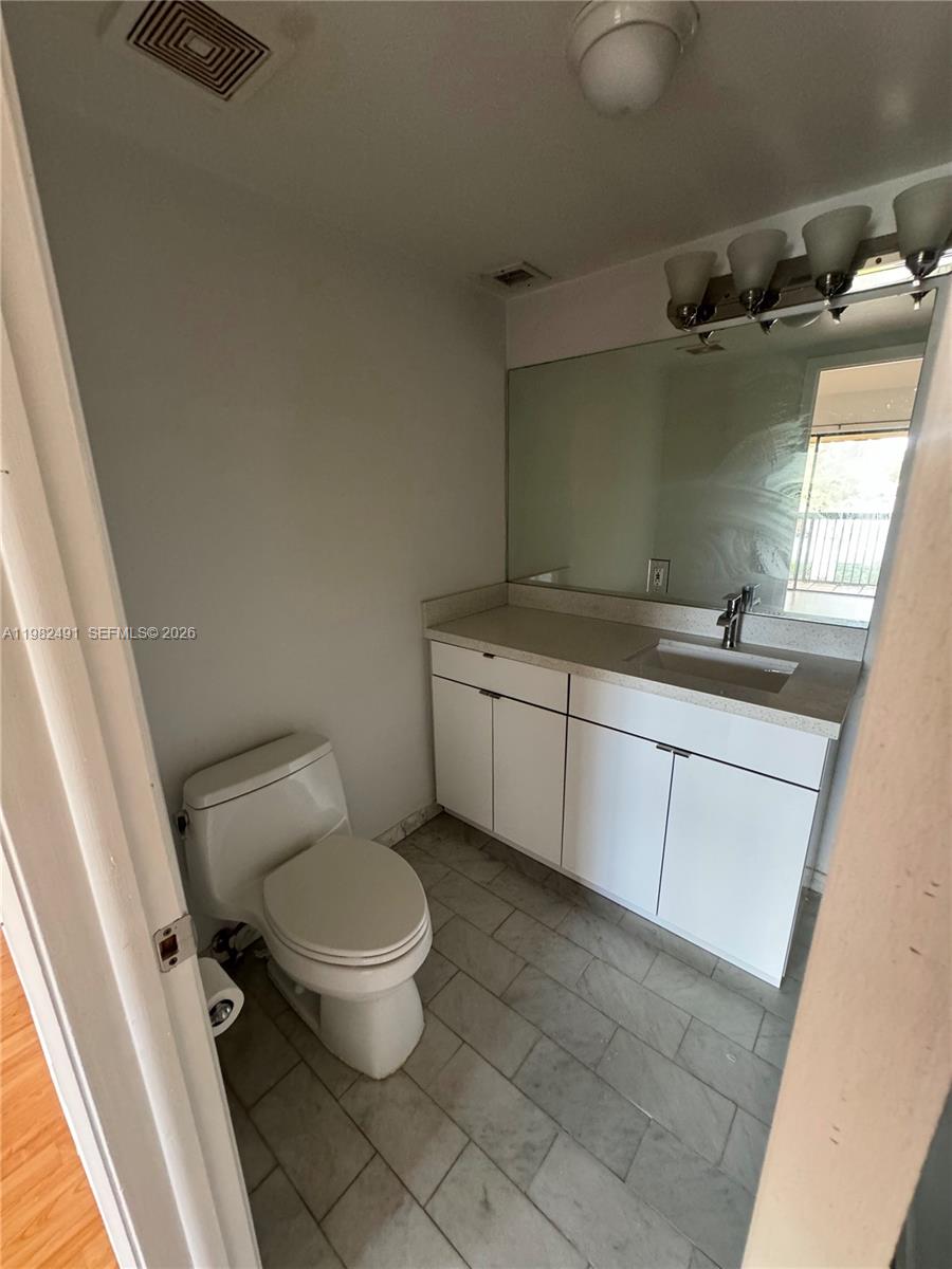 10220 Southwest 77th Court Miami, FL 33156 - Photo 10 of 12 a bathroom with a granite countertop toilet a sink and a mirror