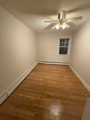 a view of an empty room with chandelier fan and a window