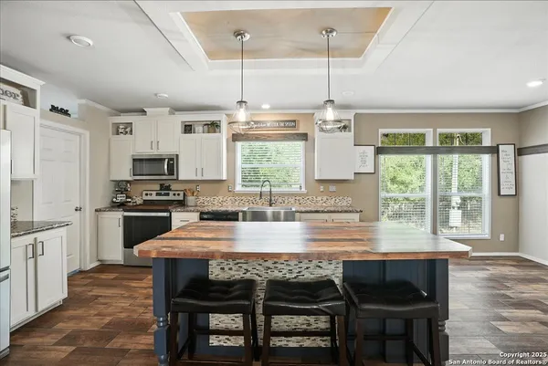 a kitchen with kitchen island granite countertop a stove a sink a dining table and chairs with wooden floor