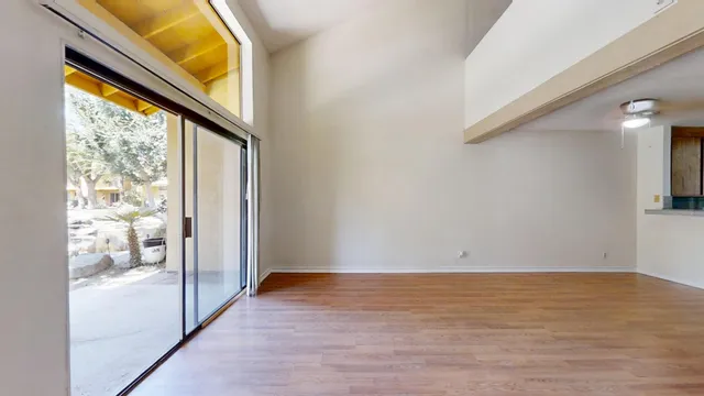 a view of an empty room with wooden floor and a window
