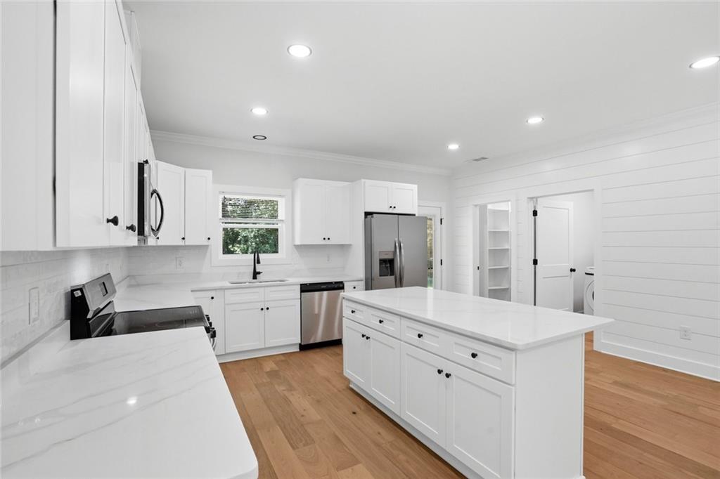 134 Henry Meyer Road Winterville, GA 30683 - Photo 12 of 34 a large white kitchen with a stove a sink dishwasher and a refrigerator with wooden floor