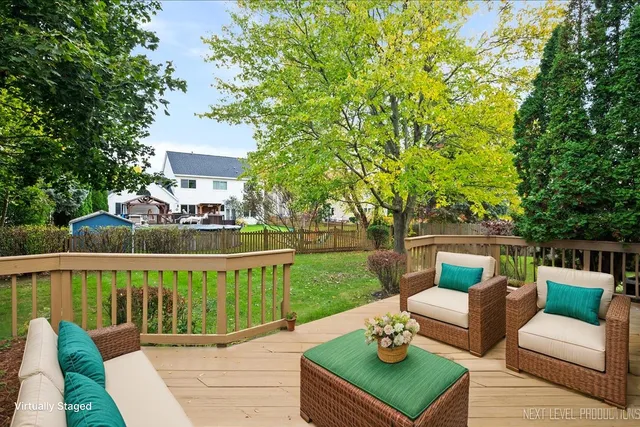 a view of a patio with couches table and chairs under an umbrella with large trees