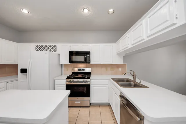 a kitchen with a sink a stove and white cabinets
