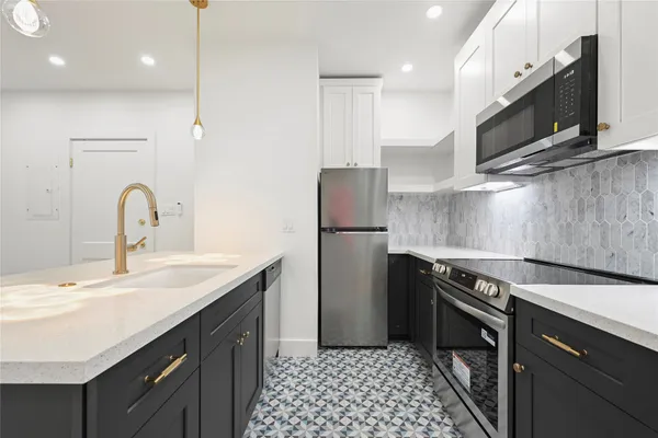 a kitchen with stainless steel appliances a sink a stove a microwave a sink a refrigerator and cabinets