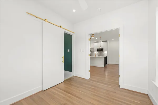 a view of a hallway with wooden floor and a bathroom