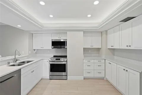 a large white kitchen with stainless steel appliances granite countertop a stove and a sink