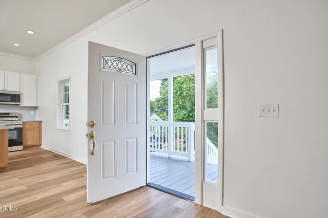 a view of an empty room with wooden floor and a window