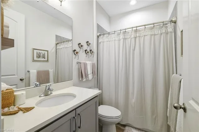 a bathroom with a granite countertop sink toilet and a mirror