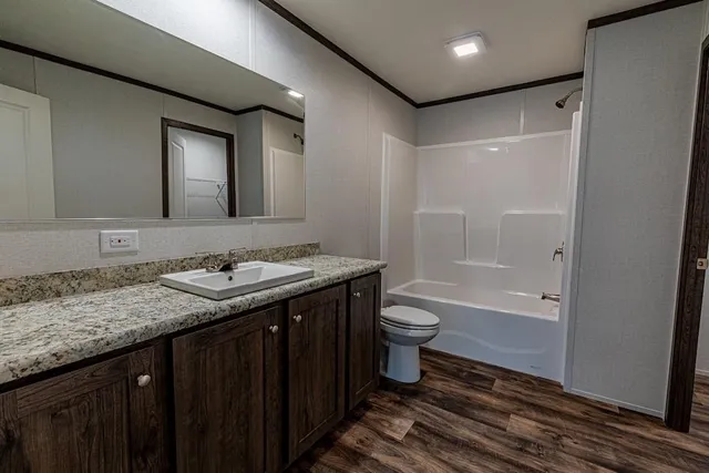 a bathroom with a granite countertop sink toilet and shower