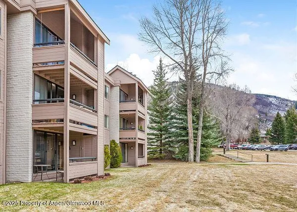 a view of a house with a yard and large trees