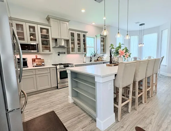 a kitchen with stainless steel appliances a stove a sink dishwasher a oven with white cabinets and wooden floor