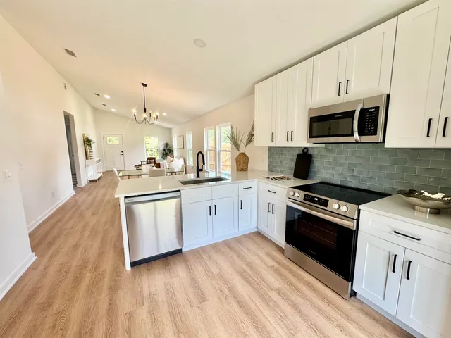 a kitchen with granite countertop a stove top oven a sink dishwasher and a refrigerator with wooden floor