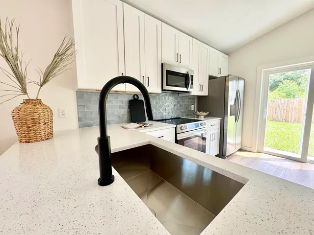 a kitchen with stainless steel appliances granite countertop a sink a stove and a refrigerator