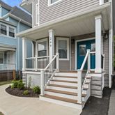 a view of a white house with a small yard and plants